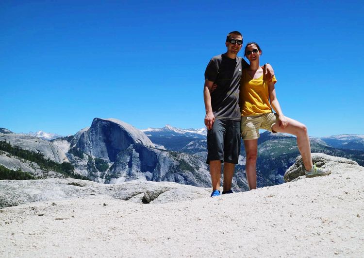 Full length of friends standing on mountain against clear sky