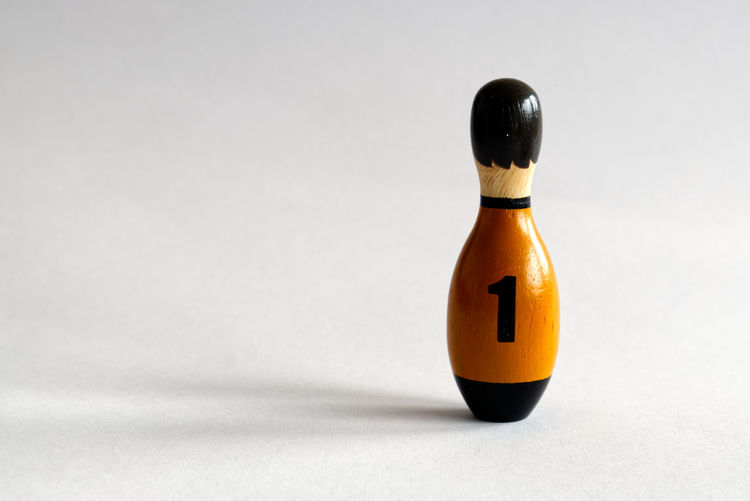 A wooden puppet in the shape of a bowling pin with a number one shirt
