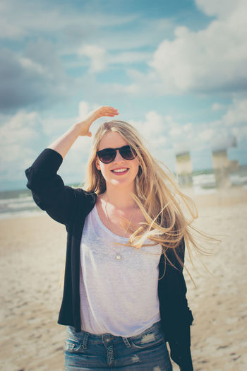 Portrait of smiling young woman wearing sunglasses at beach