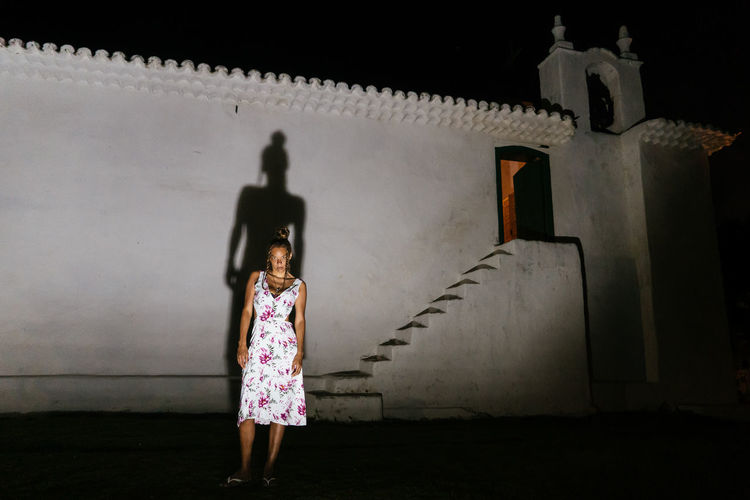 Rear view of a young woman standing against a wall in front of a church in trancoso in bahia