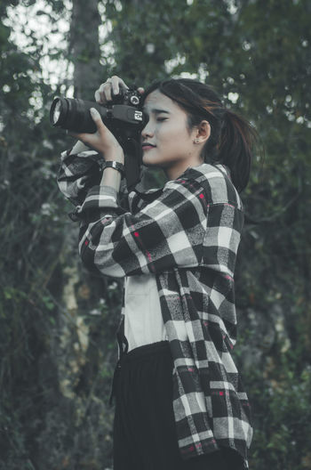 Young woman photographing camera while standing on land