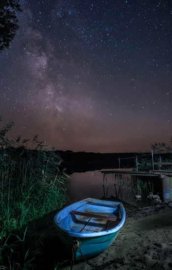 Boats moored on lake against sky at night