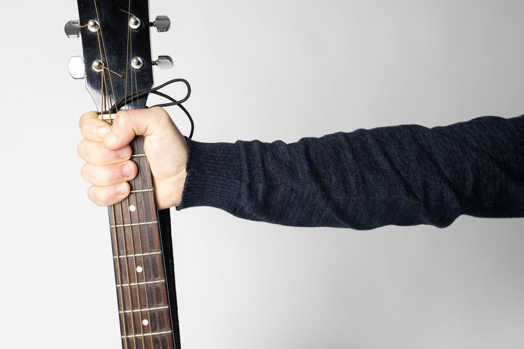 Midsection of person playing guitar against gray background