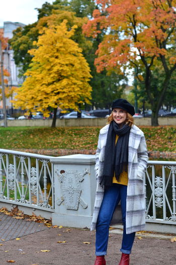 Portrait of smiling young woman standing in park during autumn