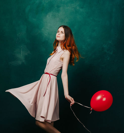 Portrait of young woman with balloons against sky