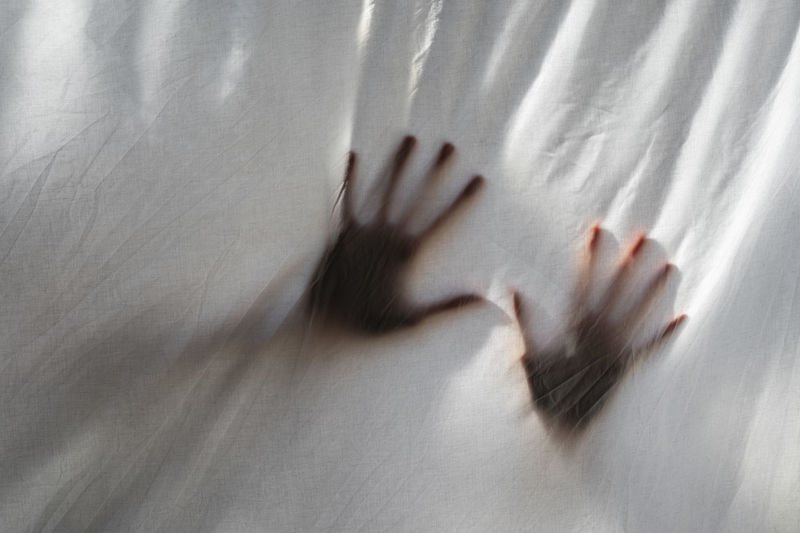 Hands shades behind a white sheet. concept about mental health, anxiety, stress, imprisonment.