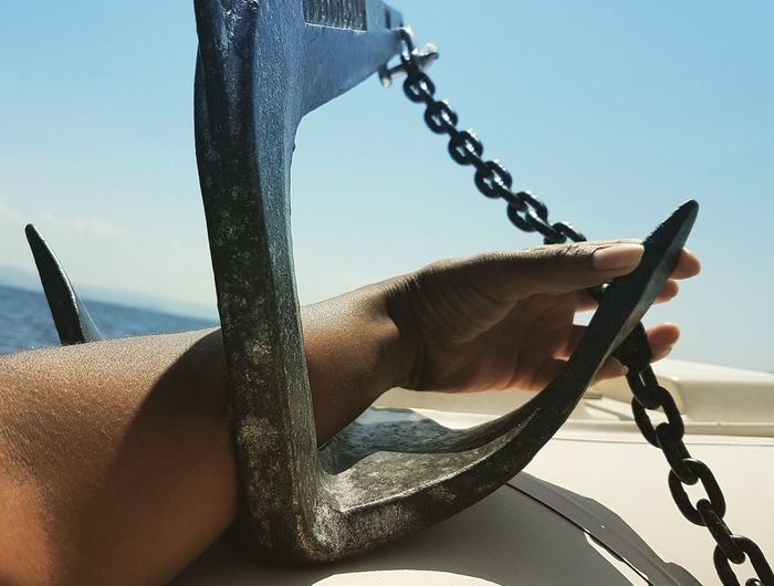 Cropped hand of person holding anchor on boat over sea