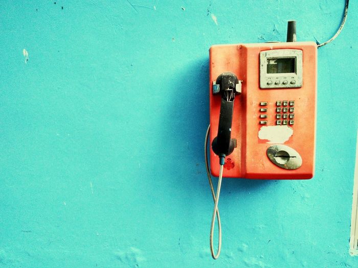 Close-up of landline phone mounted on blue wall
