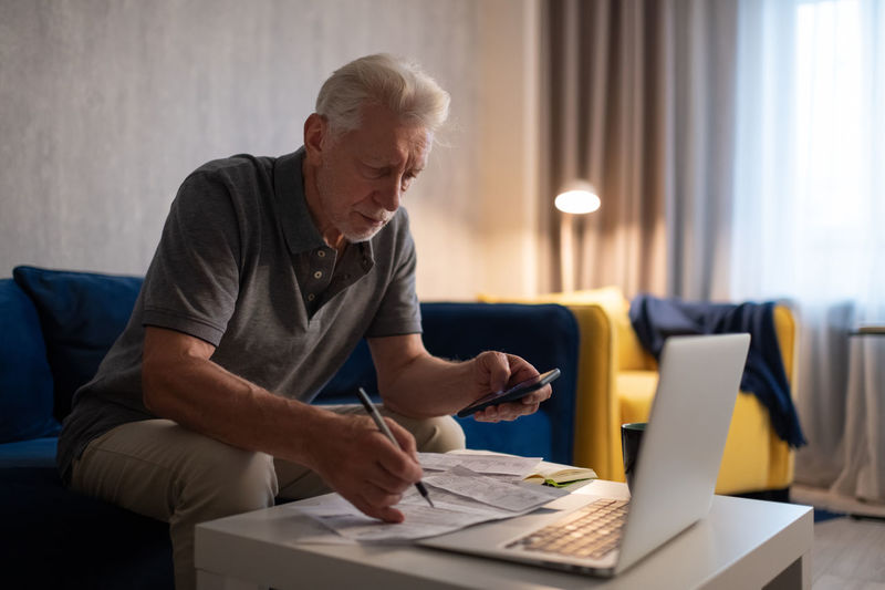 Elderly man calculating taxes at home