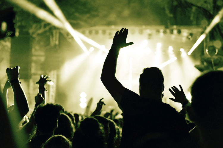 Crowd at a music concert with raising hands up, toned image