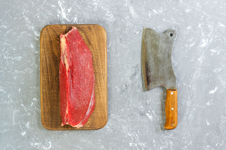 Vintage cleaver and raw pork filet on gray concrete background
