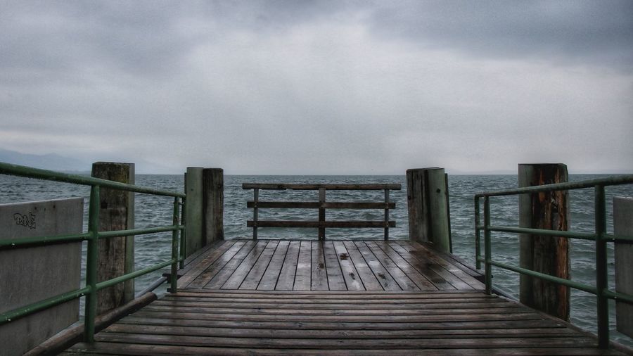 Wooden pier over sea against sky