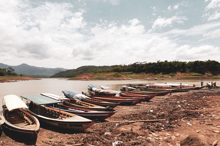 Panoramic view of boats moored on shore against sky