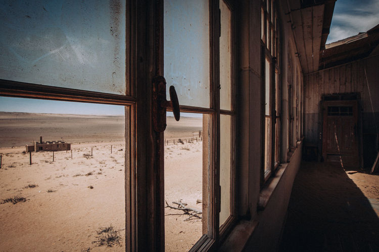 Abandoned building by sea seen through window