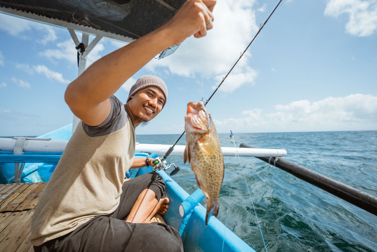 Low section of woman holding fish in sea