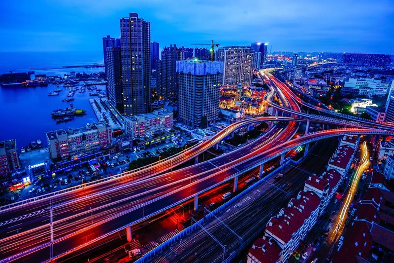 Aerial view of light trails on multiple lane highways in city at dusk