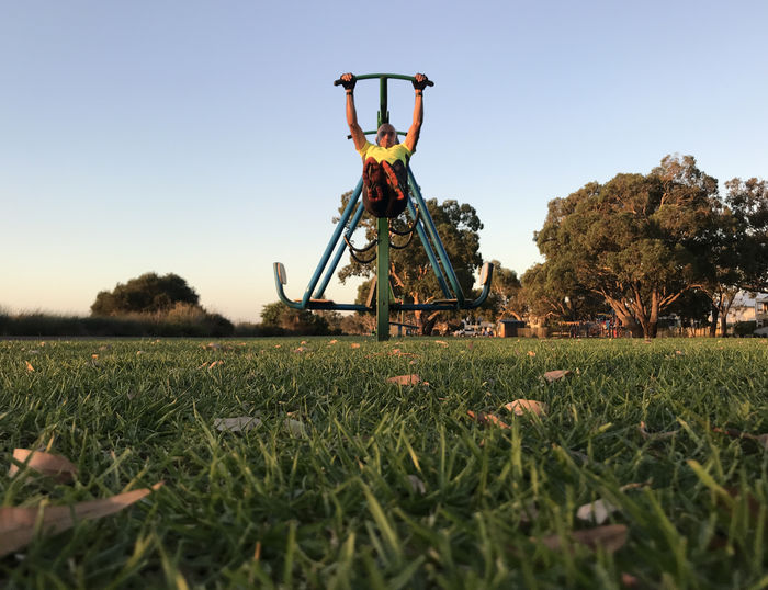 Full length of mature man exercising at park against clear sky during sunset