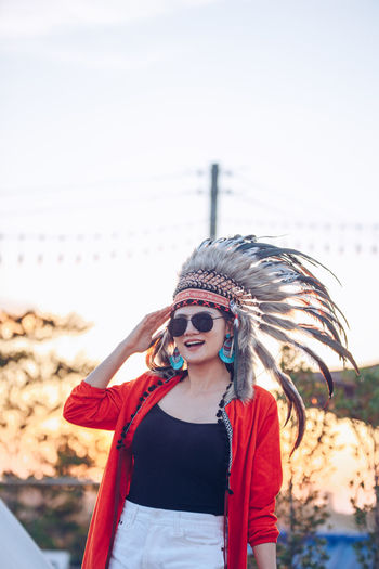 Portrait of young woman wearing headdress while standing against sky