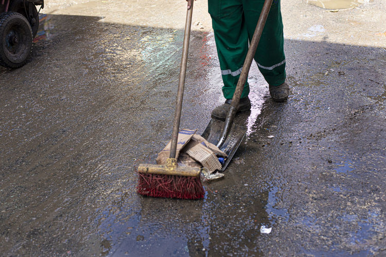 Legs of a urban cleaning worker cleaning the floor wet from the rain at the fair