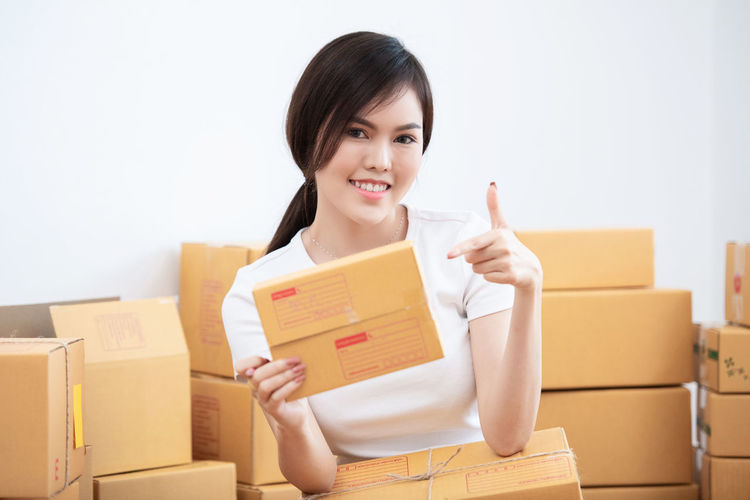 Portrait of smiling young woman holding camera in box