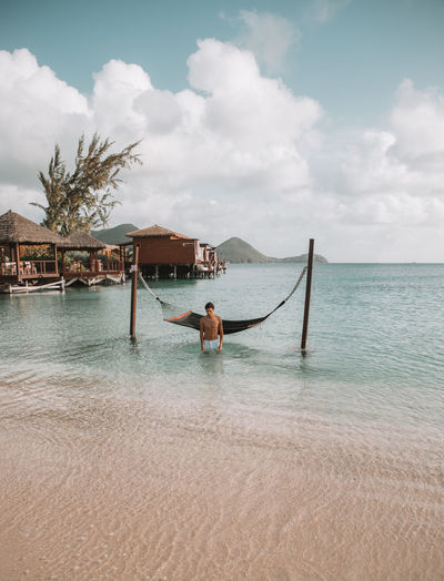 Man standing by hammock standing in sea