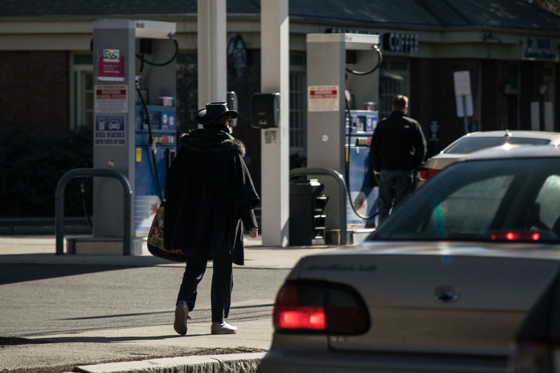 Rear view of people by cars at gas station