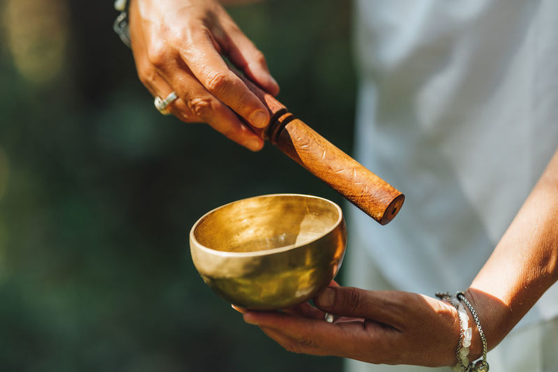 Hands of a woman playing tibetan singing bowl in nature