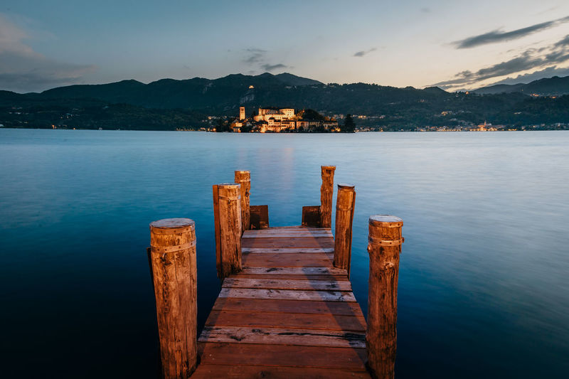 The island of san giulio with a wooden pier in the foreground at sunset, blue hour,  long exposure