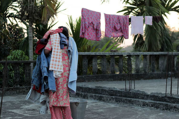 Rear view of woman removing laundry from clothesline