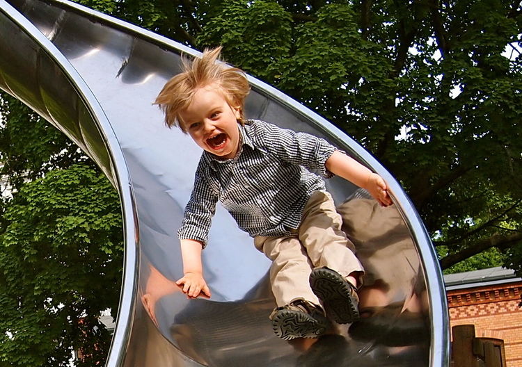 Full length of boy sliding down slide on playground