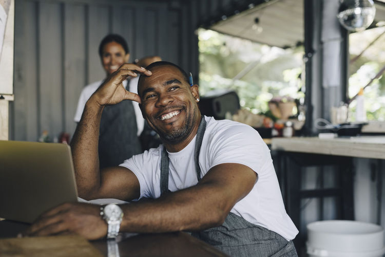 Smiling male owner with head in hand sitting food truck