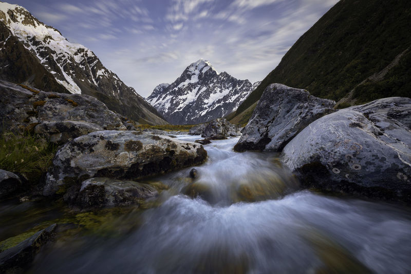 Scenic view of river flowing on rocks against sky