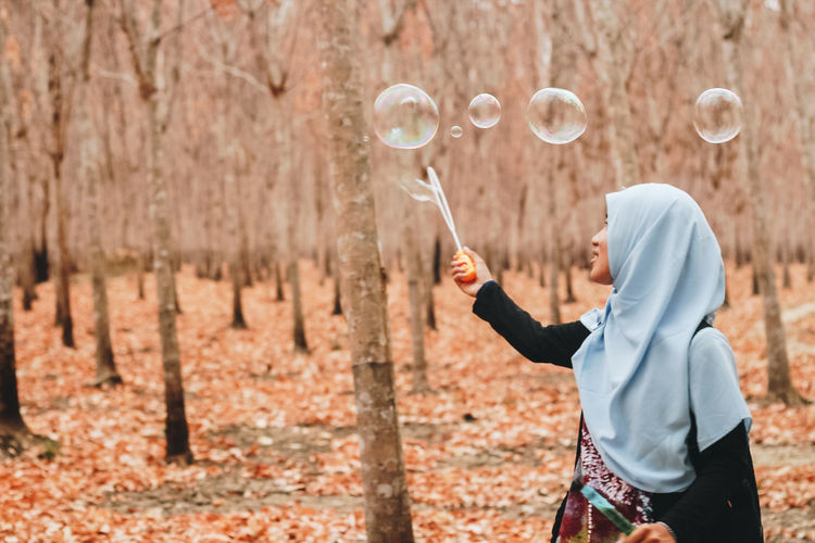 Woman looking at bubbles in forest
