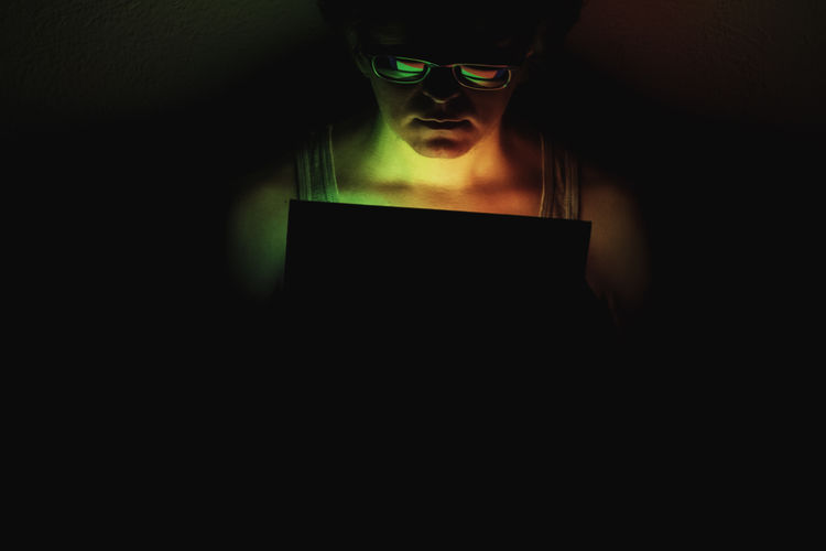 Portrait of young woman using smart phone in darkroom