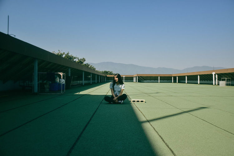 Full length of woman sitting on floor against sky