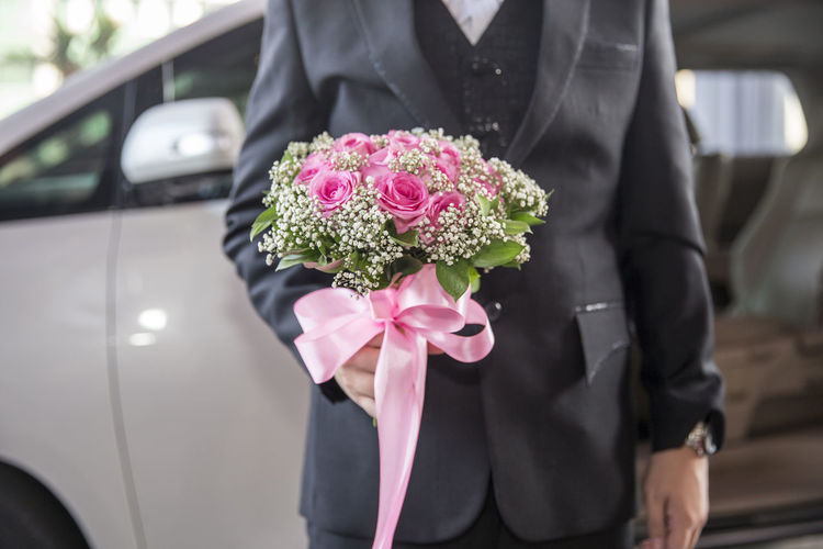 Midsection of man holding flower bouquet