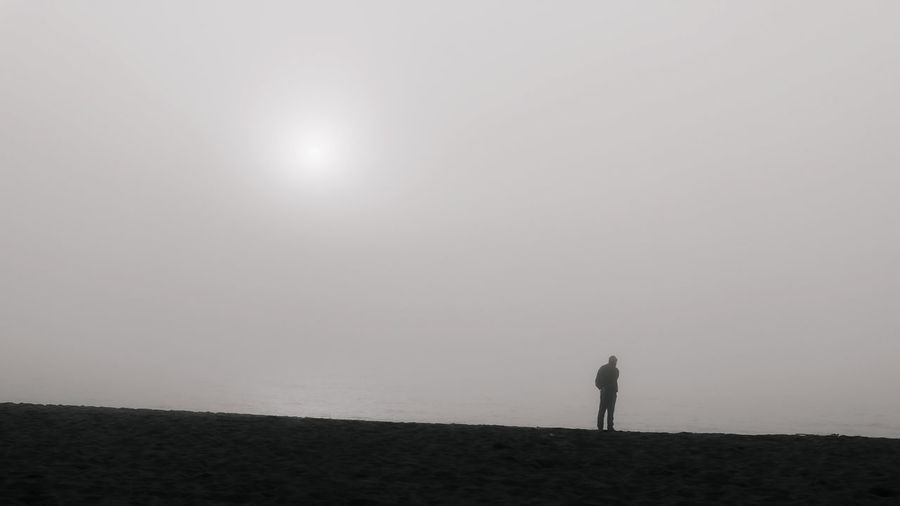 Man standing on field against sky in foggy weather