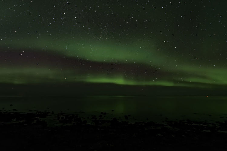 Scenic view of sea against aurora borealis at night