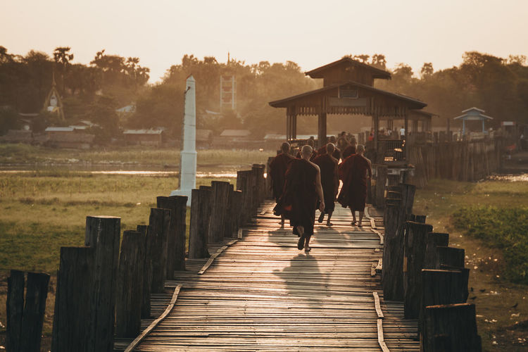 Rear view of monks walking on footbridge
