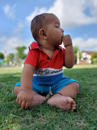 Portrait of cute baby boy standing on field