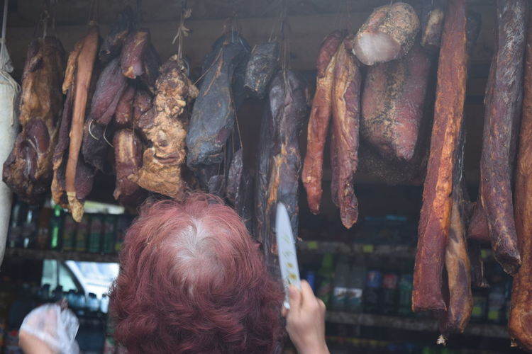 Rear view of woman standing at butcher shop