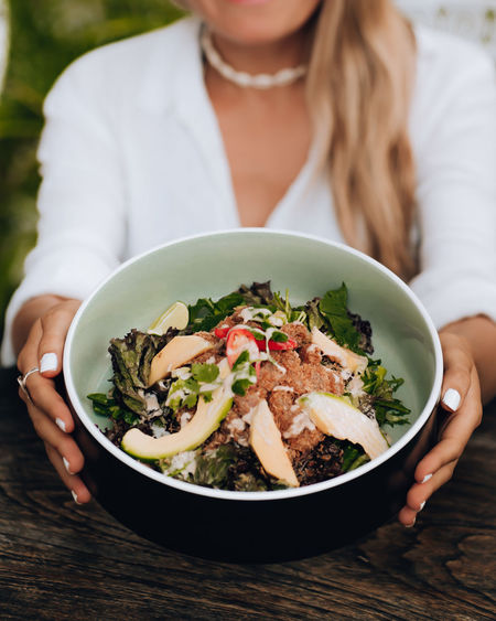 Midsection of woman holding salad in bowl