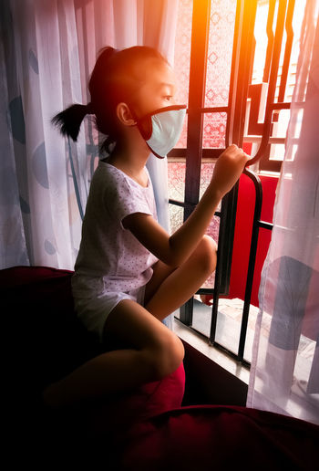 Girl sitting on window at home