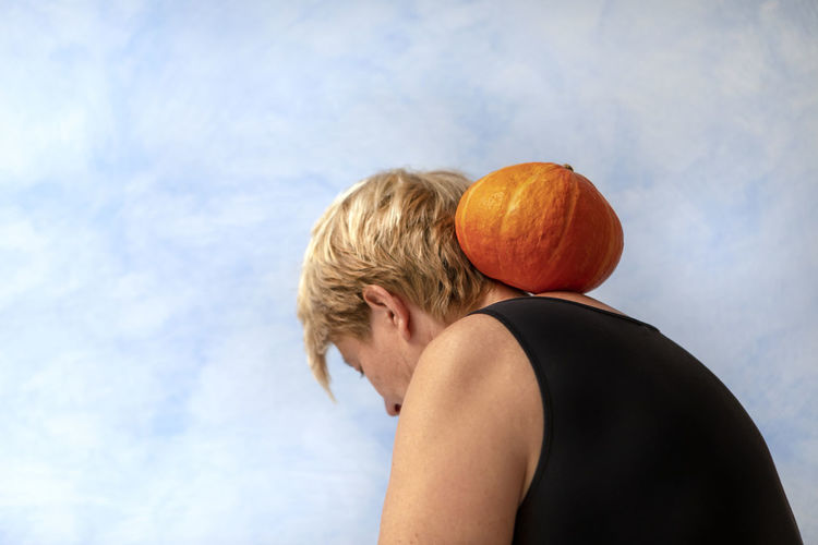 Rear view of man standing by pumpkin against sky
