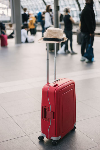 Red suitcase with a woman hat at the train station