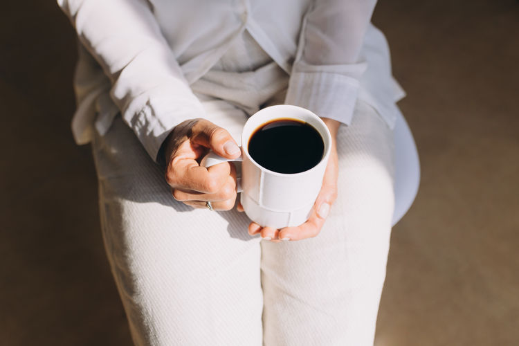 Midsection of woman holding coffee on table