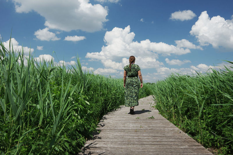 Man standing on road amidst plants against sky