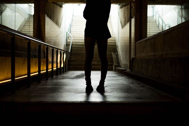 Low section of silhouette woman at underground walkway