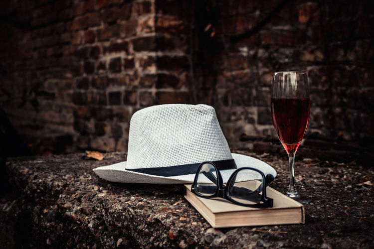 Fedora hat with book and glass of red wine.