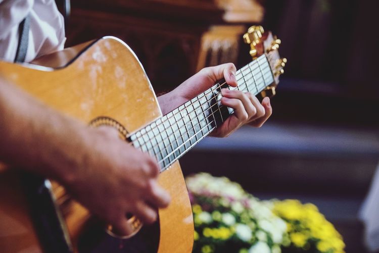 Midsection of man playing guitar